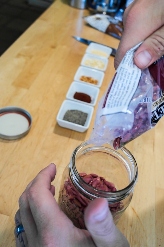 adding beans and spices to our meal in a jar