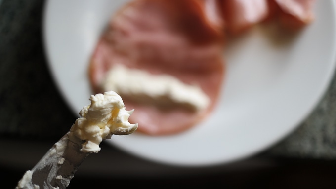 spreading cream cheese on ham