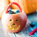 Jack-o-lantern fruit bowls made with apples and berries. Such a cute Halloween snack!