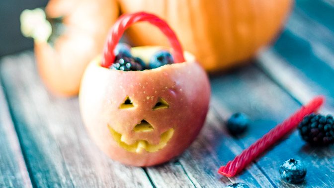 Jack-o-lantern fruit bowls made with apples and berries. Such a cute Halloween snack!
