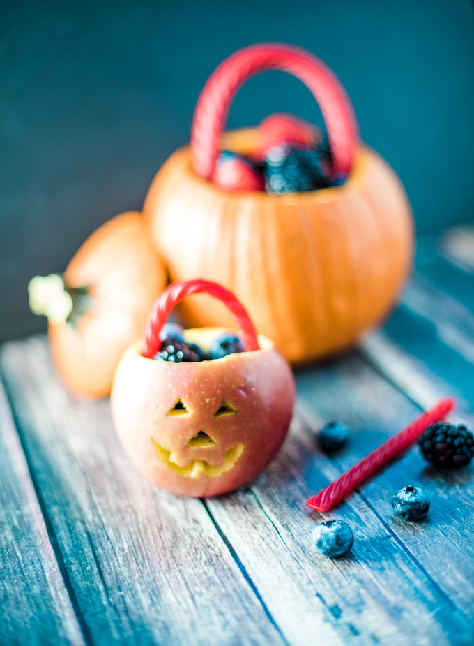 Jack-o-lantern fruit bowls made with apples and berries. Such a cute Halloween snack!