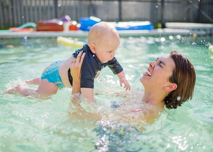 Baby splashing mom in the pool