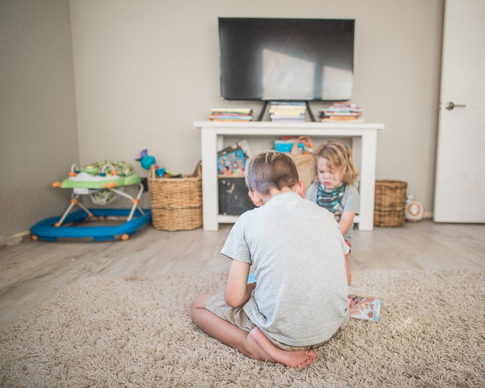 Boys reading books in front of the TV