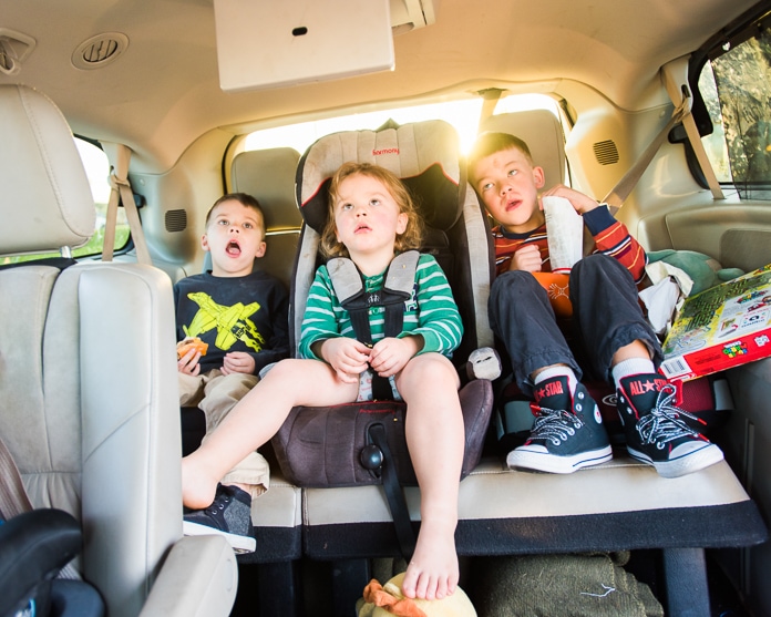Three kids in the back of a mini van