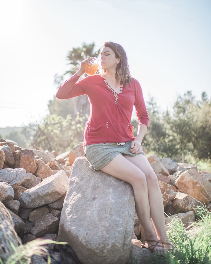 Sitting on a rock drinking orange liquid