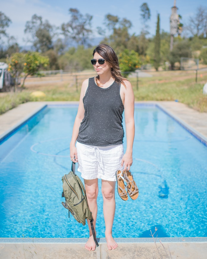 Woman holding summer shoes by the pool