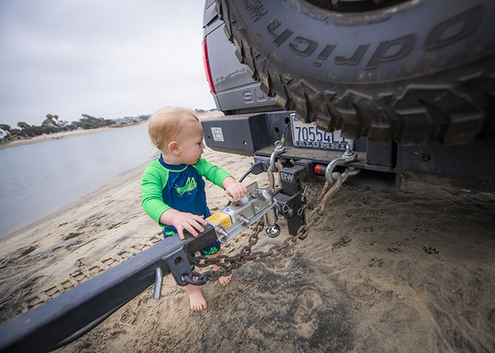 Baby plays with trailer hitch at the beach