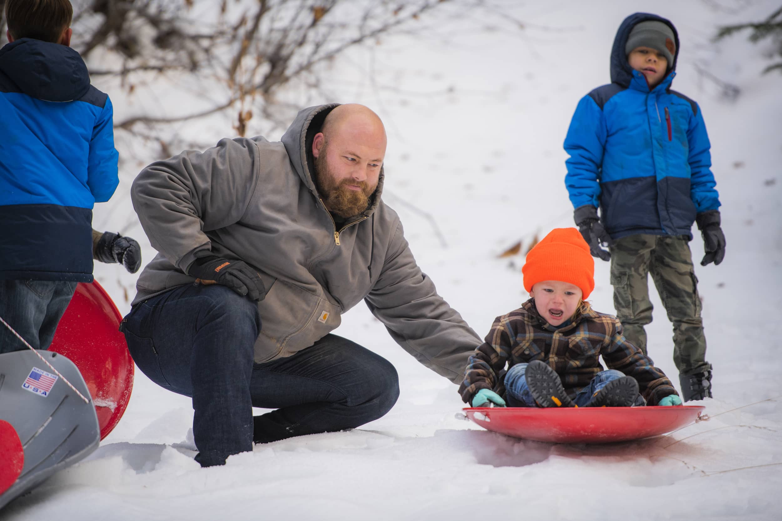 Dad pushing baby on snow sled