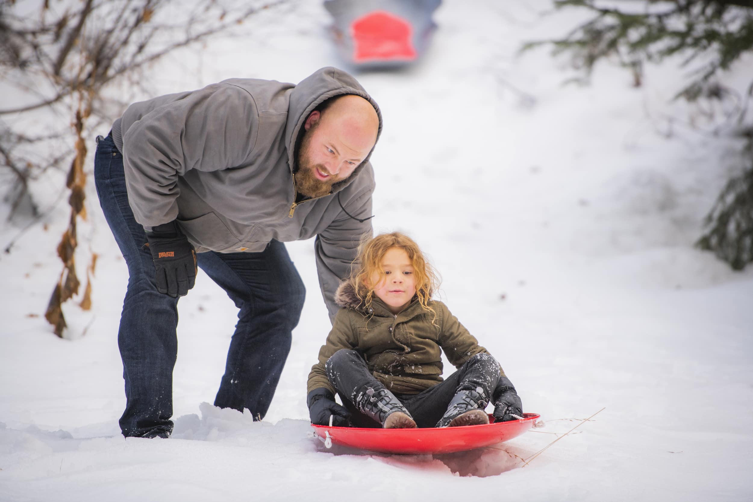 Father pushing son on snow sled