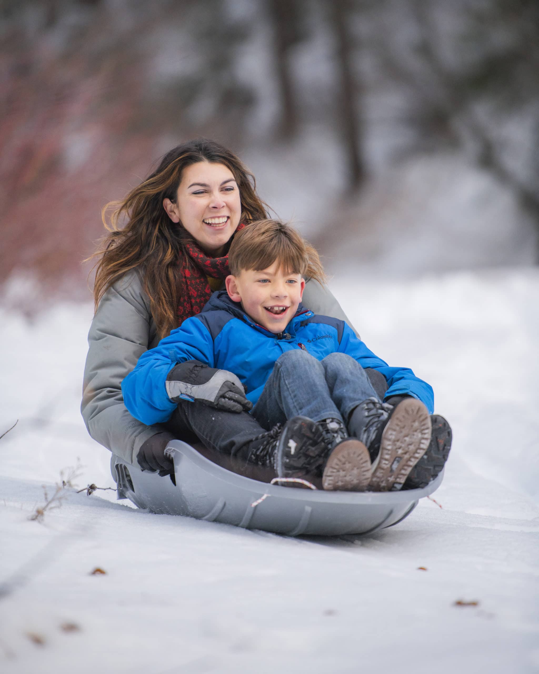 Happy mother and son sledding in merrell snow boots
