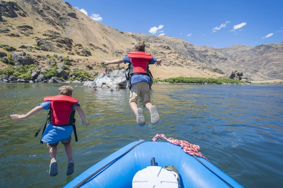 Little boy brothers jump in the snake river while american white water rafting in hells canyon