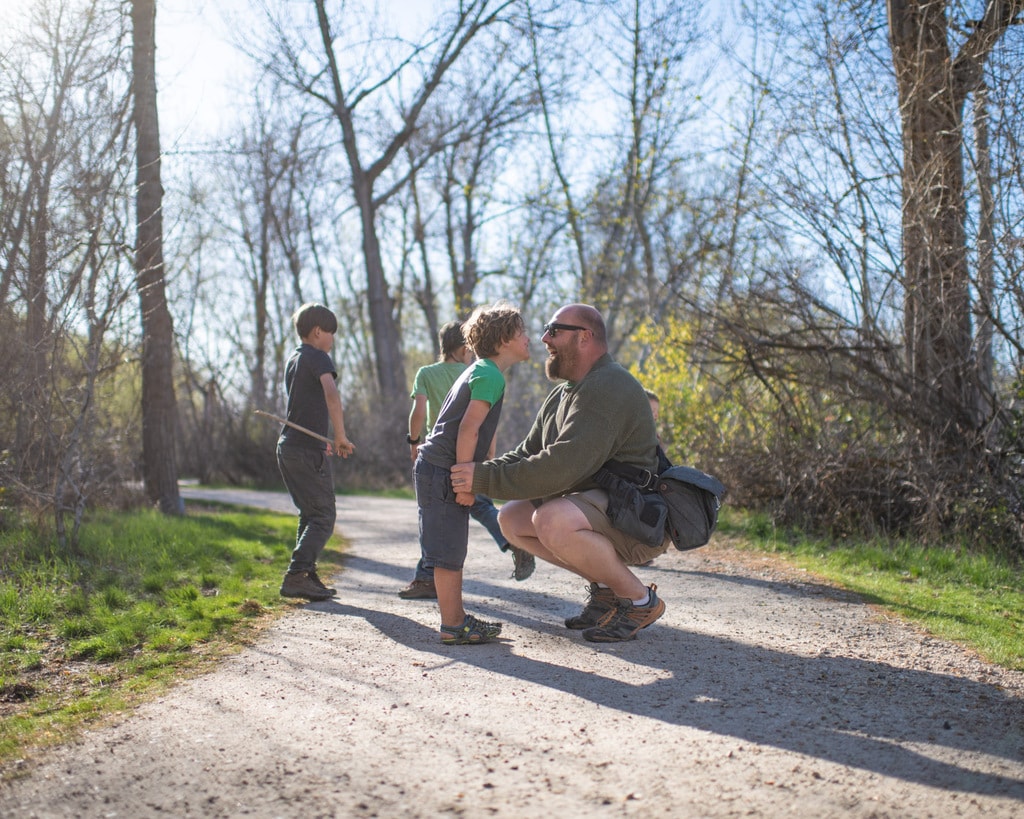 Father talking with kindergartener in woods