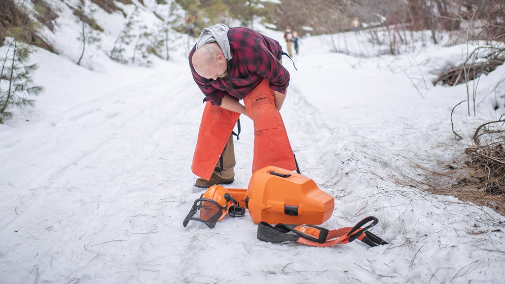Putting on stihl safety chaps in snow to use truck gear