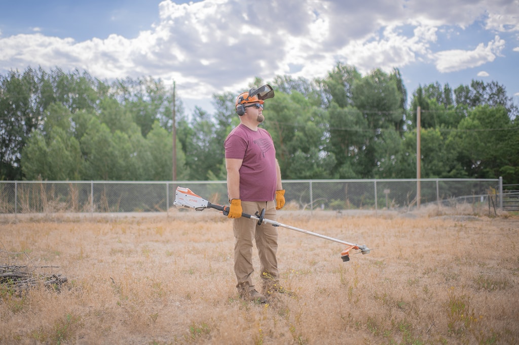 Nate day standing on farm field with stihl kma 135 and trimmer attachement