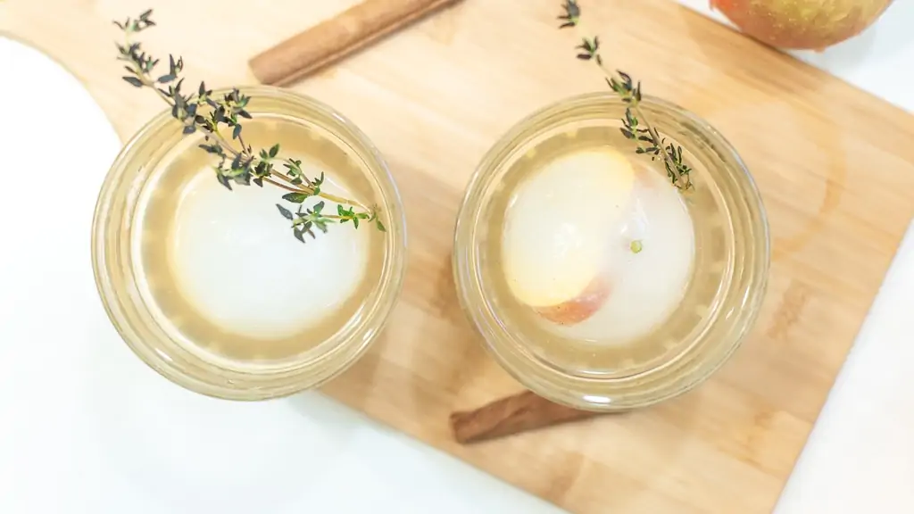 Apple cider bourbon cocktail with ice molds and thyme and cinnamon