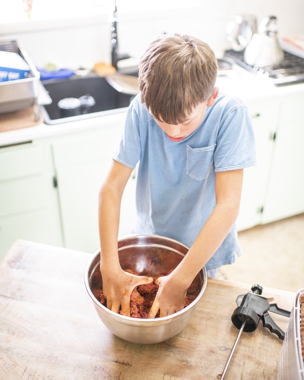 Olin day using his hands to mix in seasoning for beef jerky with a dehydrator