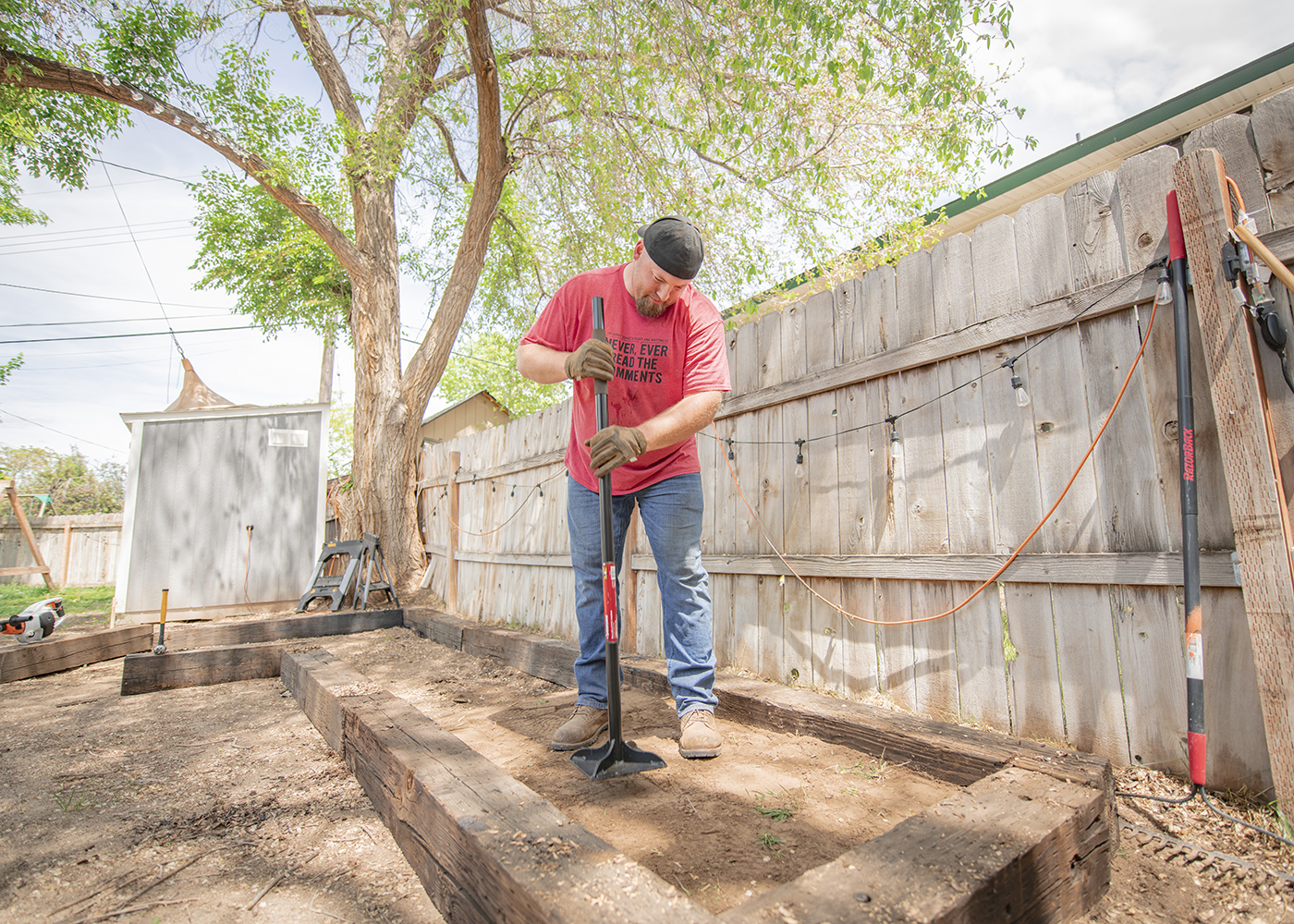 Nate day tamping down dirt in backyard remodel for traeger smoker